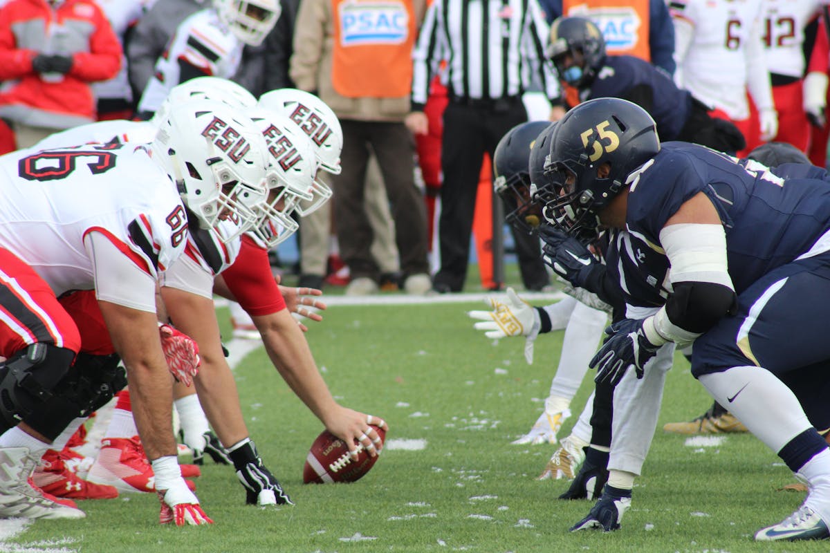 Football coaches standing on the sideline wearing headsets and communicating during a game