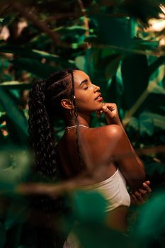 A serene portrait of a young woman surrounded by lush green foliage, embodying elegance and tranquility.