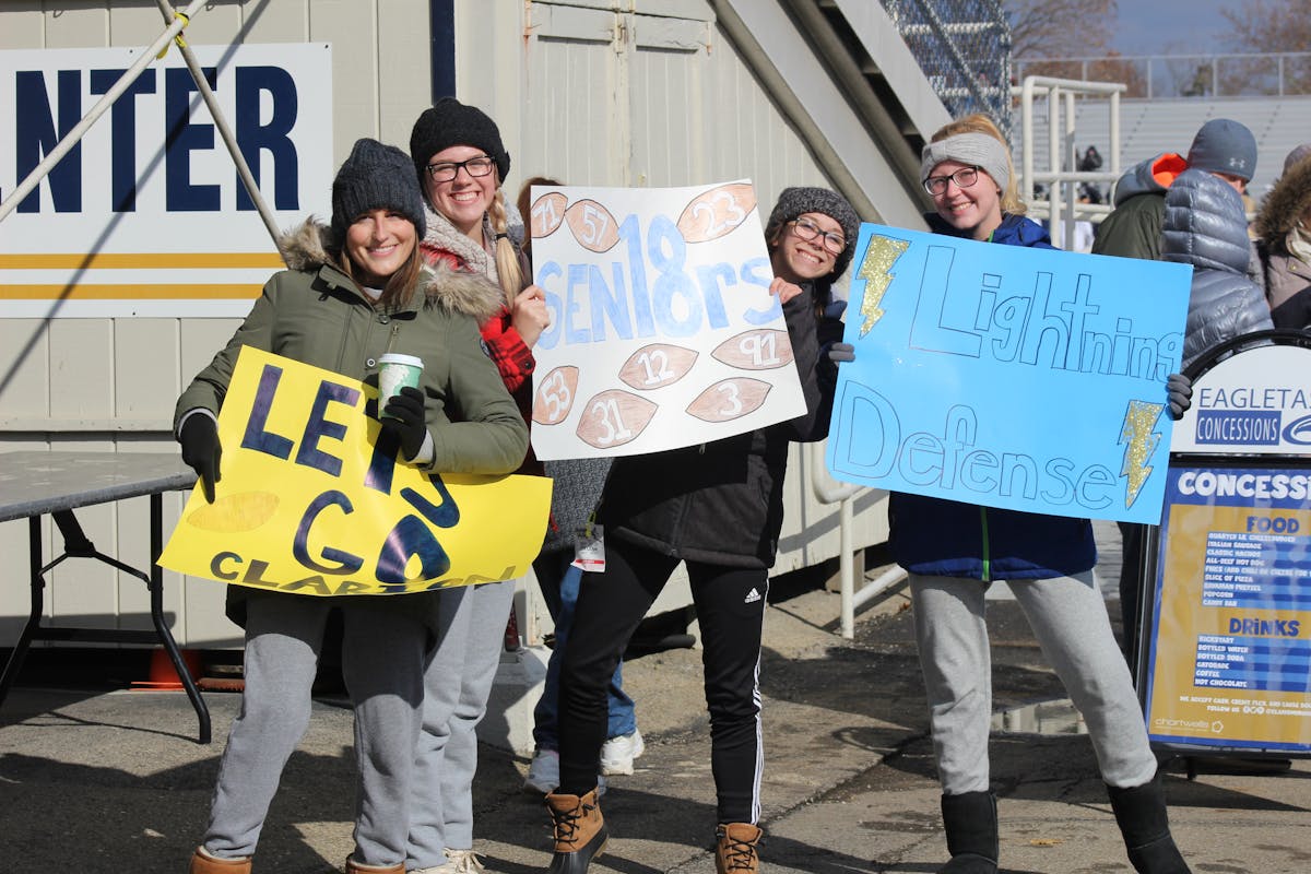 Football players huddled together on the field listening to a teammate or captain