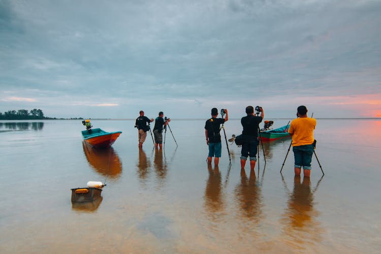 Photographers Standing In Water At Dusk