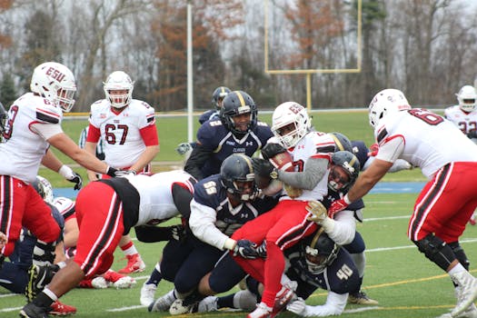 College football players in action during an intense tackle on the field showcasing teamwork and competition.