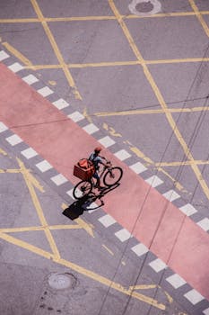 Aerial view of a courier delivering a package on a bicycle in city traffic.
