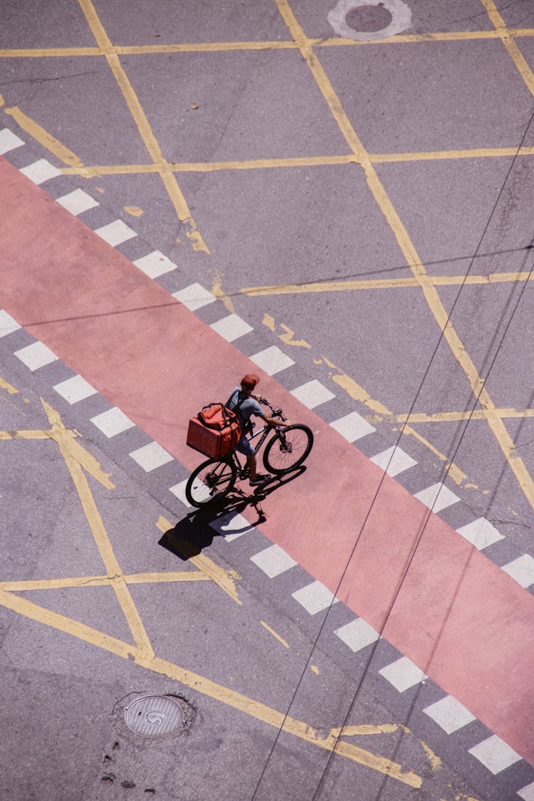 Deliveryman With Package Riding Bike On Road