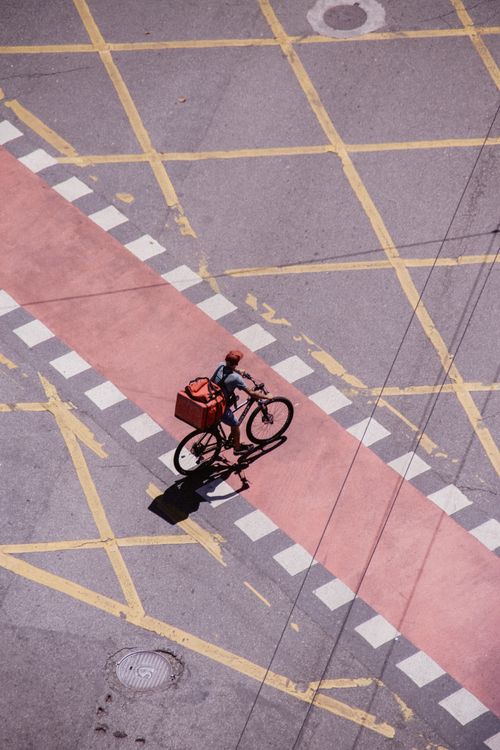 Free Aerial view of a courier delivering a package on a bicycle in city traffic. Stock Photo