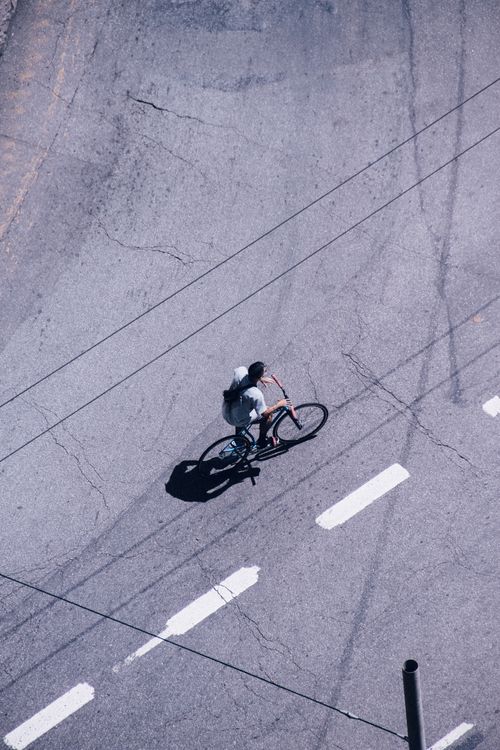 Free High-angle shot of a man cycling on a city street, highlighting urban transportation. Stock Photo