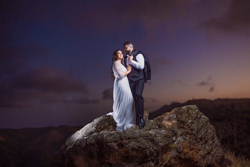 Newlyweds Posing on Top of a Boulder at Night
