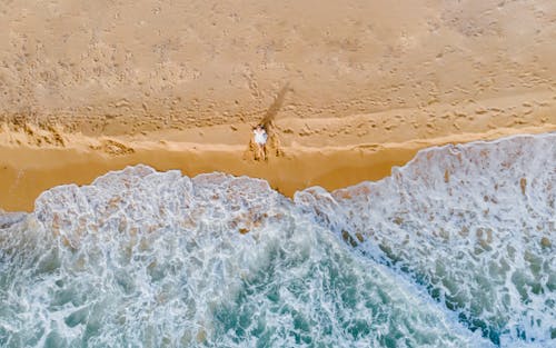 Aerial Footage of a Yellow Sandy Beach and Waves with Sea Foam