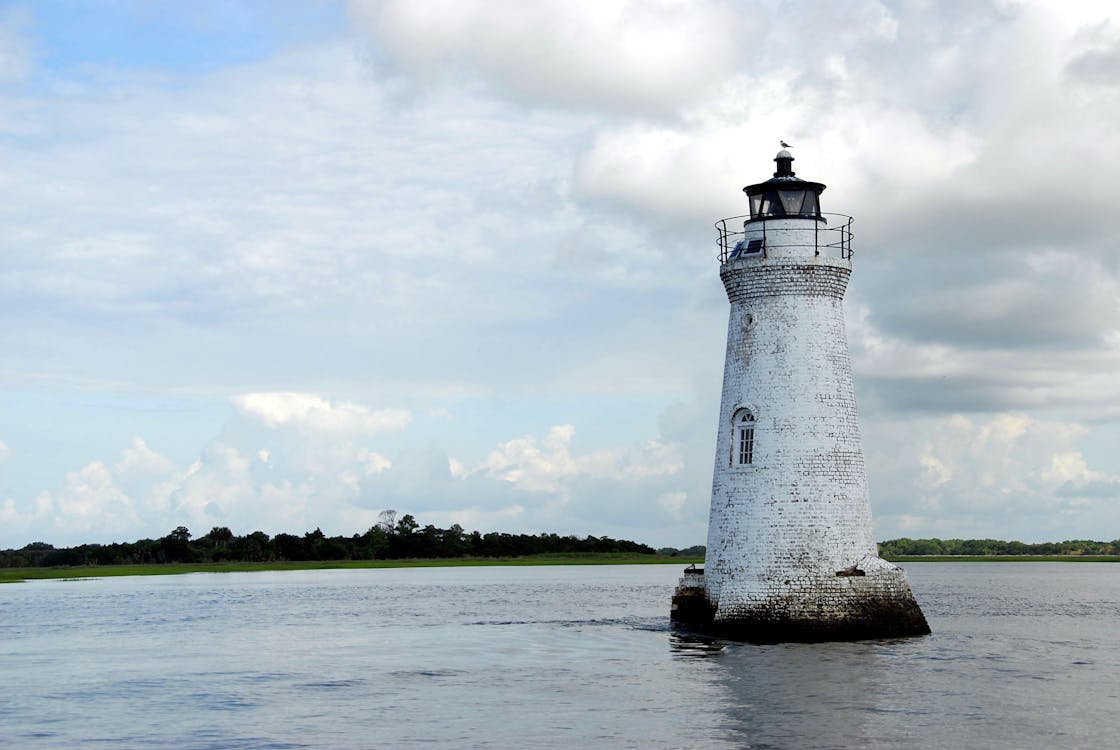 бесплатная Белый маяк посреди моря Стоковое фото