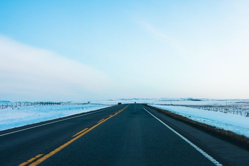 Free Empty road through snowy landscape near Calgary, Alberta, Canada. Ideal for travel and adventure themes. Stock Photo