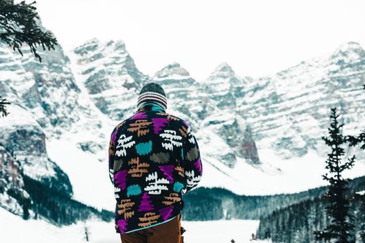 Person in vibrant jacket against snowy Banff mountain background.