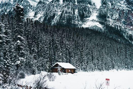 A serene snowy cabin set against the majestic mountains of Banff National Park in winter.