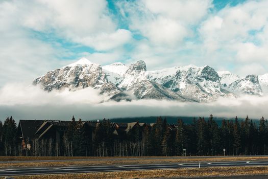Stunning view of snow-capped mountains in Canmore, Alberta, with a forest and cabins.