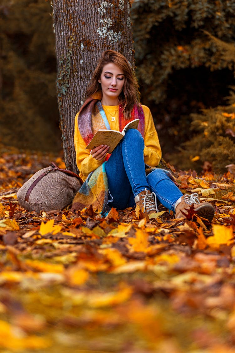 A Woman Reading A Book Outdoors 