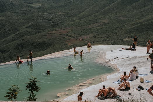 People relax in a natural infinity pool with a stunning mountain backdrop, ideal for summer tourism and travel.