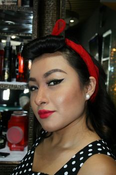 Portrait of young woman with vintage style, red bow, and polka dot dress.