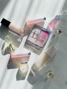 Elegant flat lay featuring premium cosmetics and perfumes on a sunlit surface.