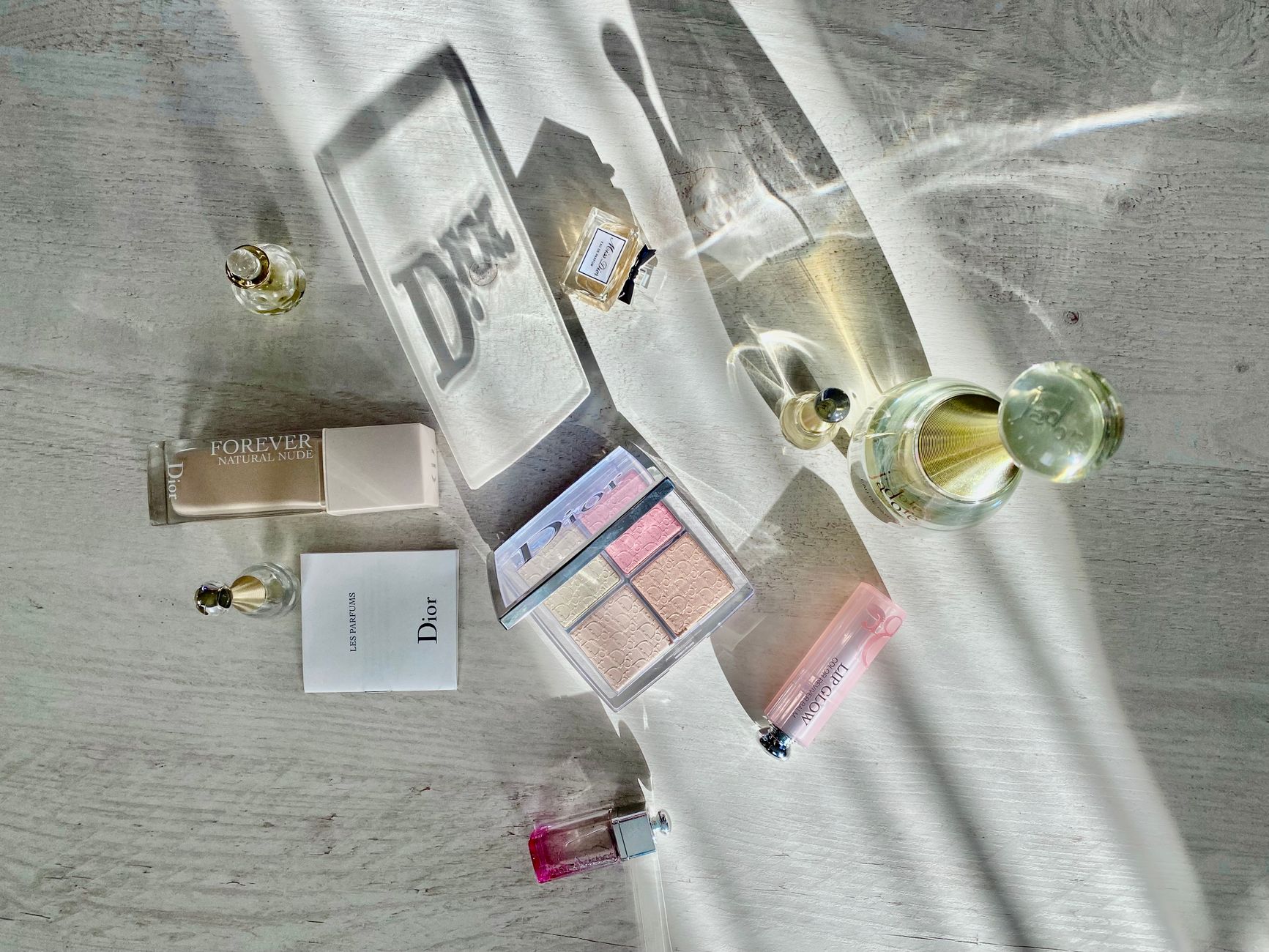 High-angle shot of Dior cosmetics and perfumes casting artistic shadows.