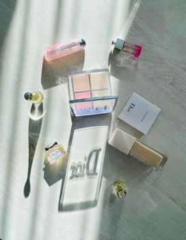 A stylish Dior cosmetics arrangement highlighted by natural sunlight on a wooden surface.