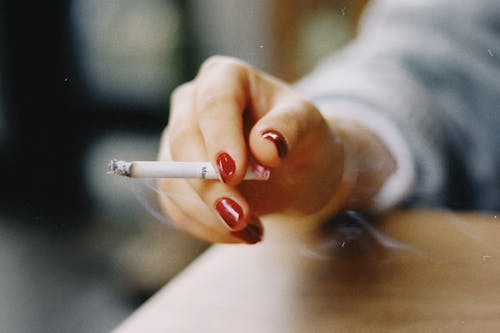 Close-up of Woman with Red Nails Holding a Burning Cigarette 