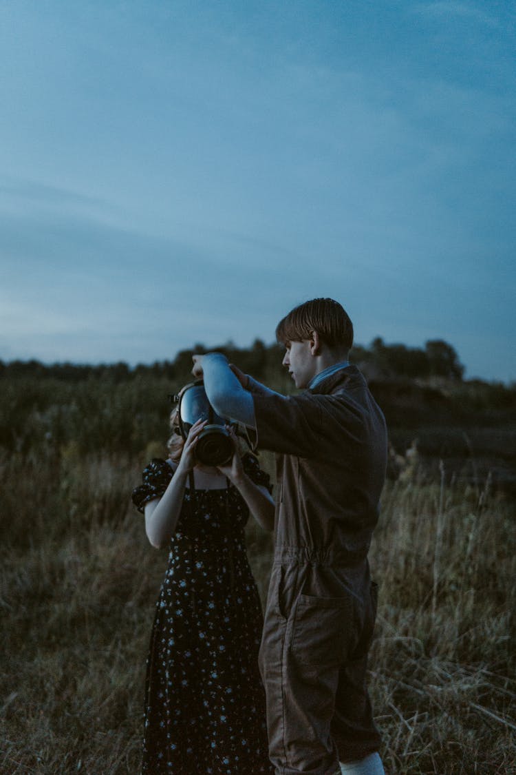 Young Man Helping A Woman To Put On A Gas Mask 