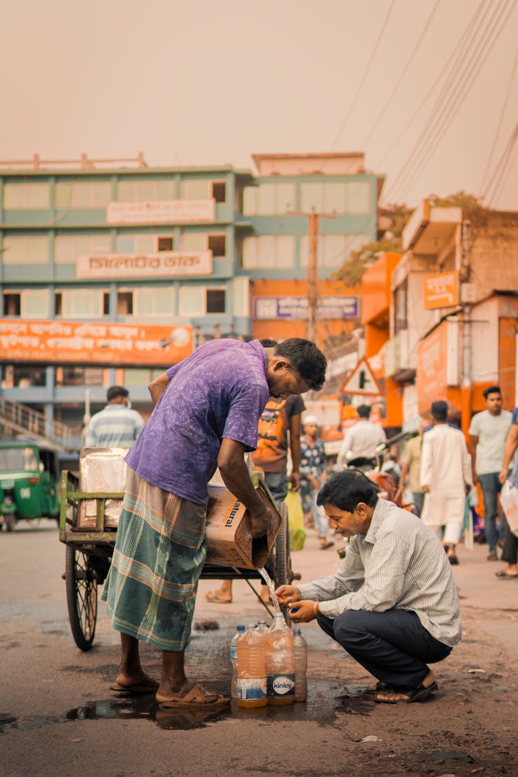 Man Filling Plastic Bottles With Liquid From A Large Bottle 