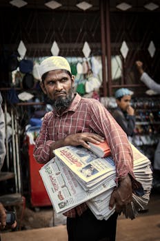 Candid shot of a street vendor selling newspapers in a bustling urban bazaar.