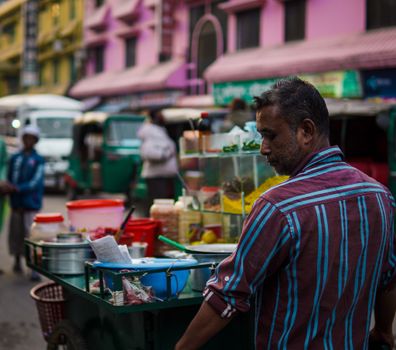 A street vendor prepares traditional food in a bustling city setting, capturing lively urban culture.