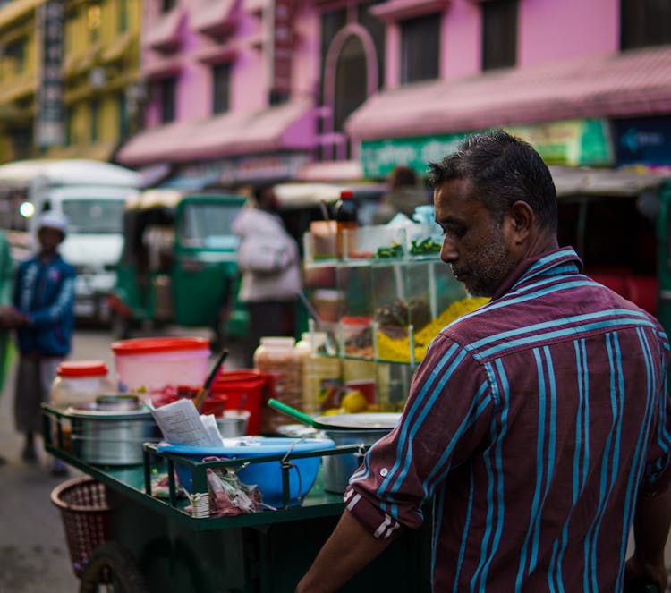 Candid Picture Of A Man With A Food Cart On The Street 