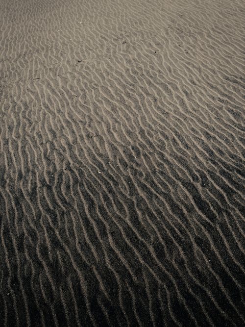 Free A detailed view of rippling sand patterns in a desert landscape, creating a textured effect. Stock Photo