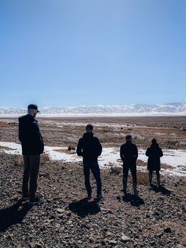 Four people standing in a snowy desert landscape of Kazakhstan under a clear blue sky.