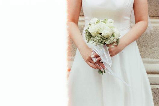 Bride in a wedding dress holding a white rose bouquet, perfect for wedding themes.