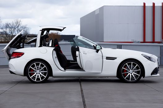 White convertible sports car with its roof raised on an urban rooftop.