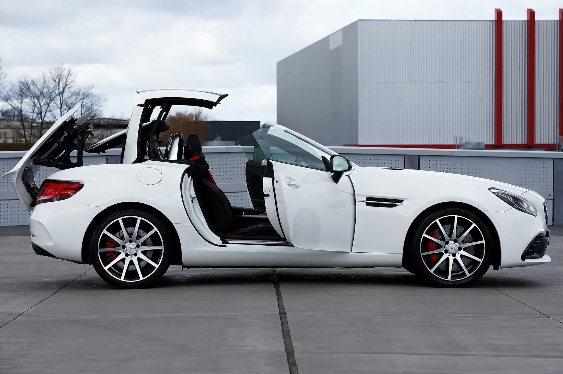White convertible sports car with its roof raised on an urban rooftop.