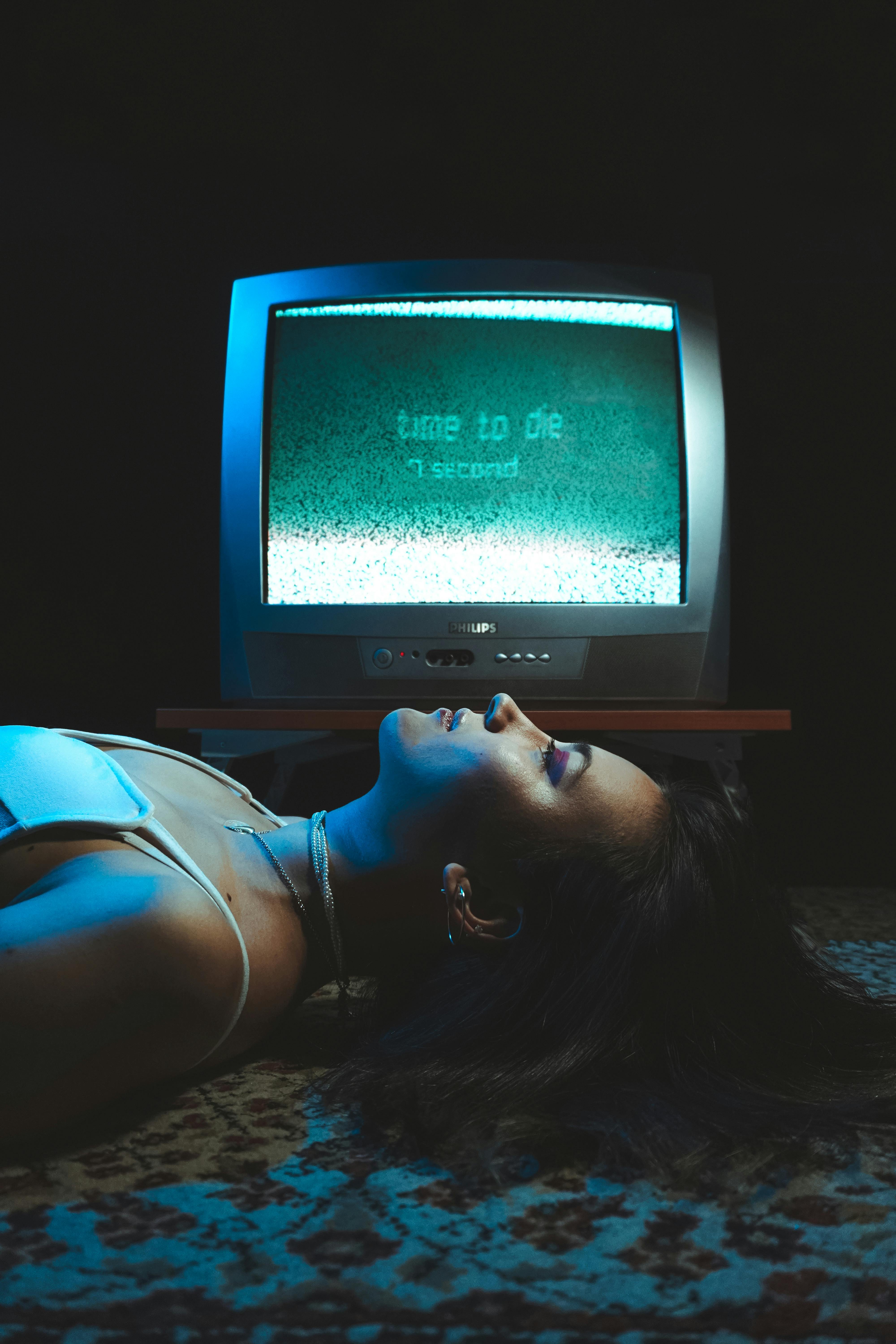 woman lying on rug by obsolete television with time to die sign