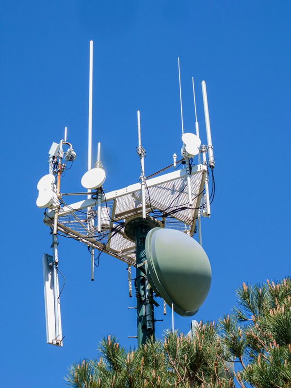 Communications tower with satellite dishes against blue sky