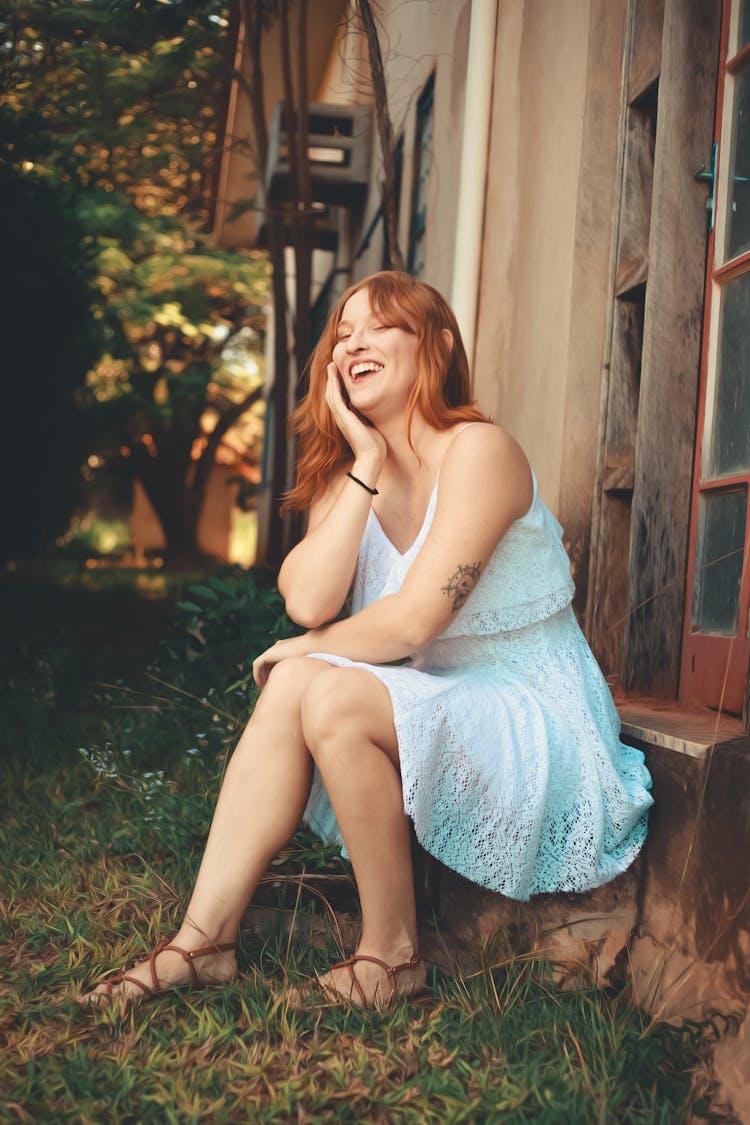 Woman Sitting In Blue Dress And Laughing