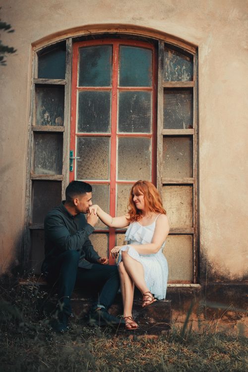 Free Loving couple sitting outside an old building, sharing a romantic moment with smiles. Stock Photo