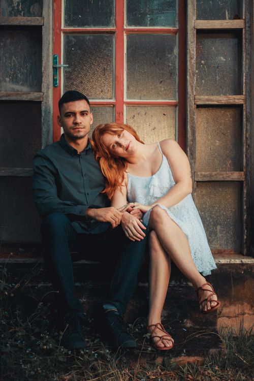 Free A couple sitting together by a rustic door, capturing a tender moment. Stock Photo