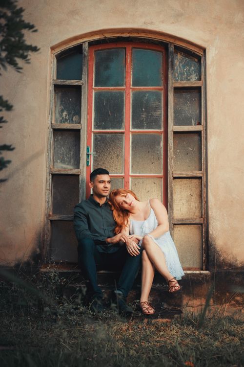 Free Couple sitting by a rustic door, capturing a romantic and serene moment. Stock Photo