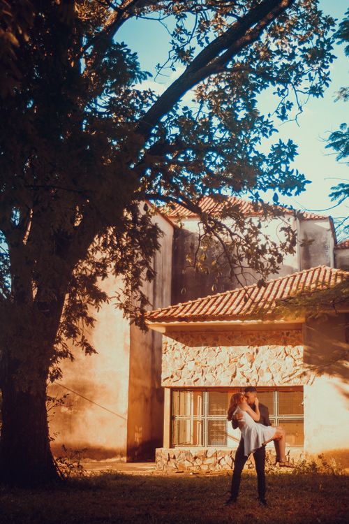 Free A loving couple shares a romantic moment outdoors near a rustic building in summer. Stock Photo