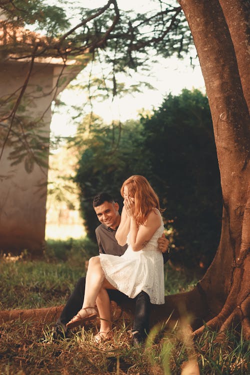 A Couple Sitting under a Tree and Smiling 