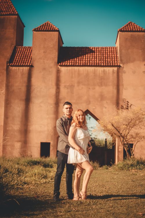 Free Romantic portrait of a couple posing together in front of a rustic building, highlighting love and togetherness. Stock Photo