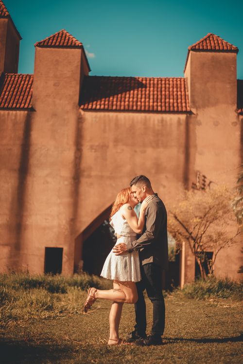 Free A young couple sharing a romantic moment in front of a rustic castle in summer. Stock Photo