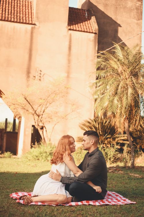 Free A couple enjoying a romantic picnic outdoors with a warm embrace against a sunlit backdrop. Stock Photo