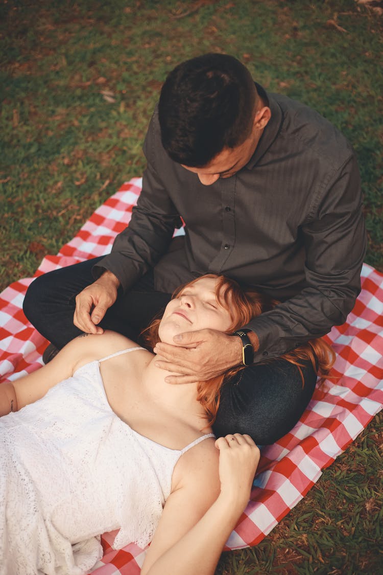 Woman Lying Down And Man Sitting On Picnic Blanket