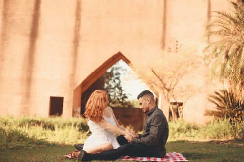 Free A couple having a romantic picnic outdoors, sitting on a blanket under warm sunlight. Stock Photo