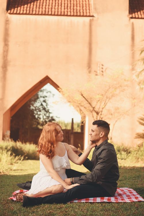 Free Young couple enjoying a romantic picnic outdoors with affectionate gestures. Stock Photo