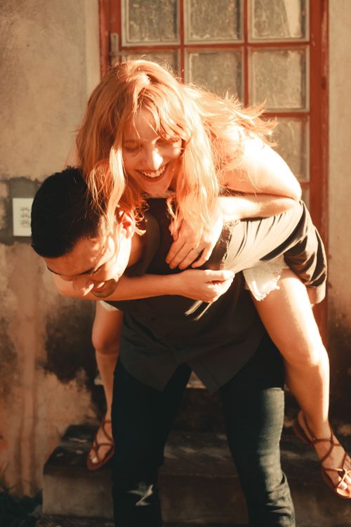 Free Joyful couple having fun with a piggyback ride in warm sunlight. Stock Photo
