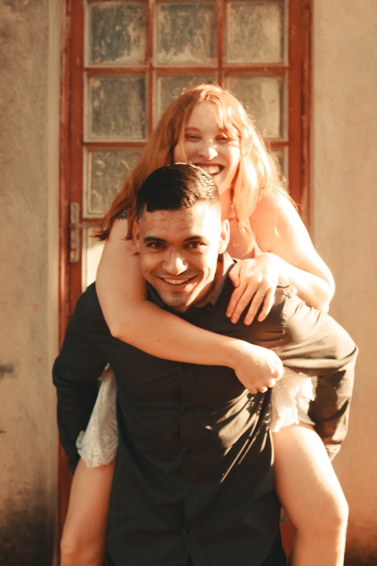 Smiling Man Carrying A Woman On His Back