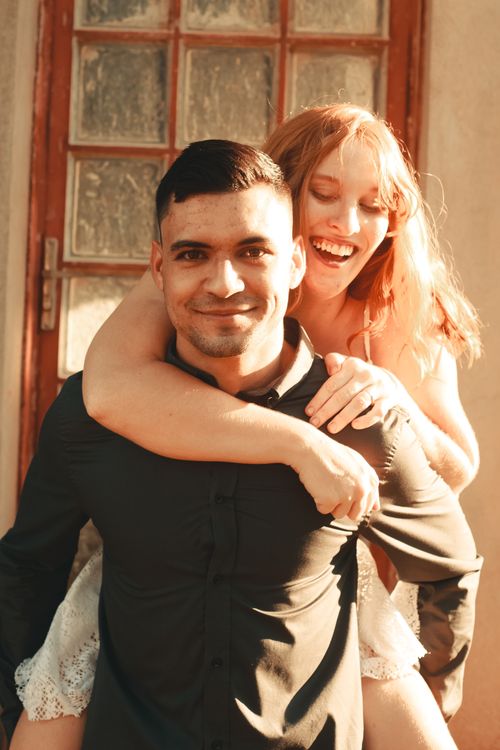 Free A joyful couple sharing a playful piggyback ride outdoors, exuding affection and happiness. Stock Photo
